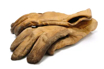 A pair of well-worn leather work gloves against a white background.